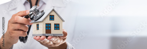 Valokuva Doctor examining house model with stethoscope