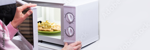 Woman Heating Food In Microwave