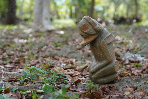 Taino Antique Stone Cemi Idol God Figure standing over rocks on the ground, close up. Taino Mythology. © Leo Matos