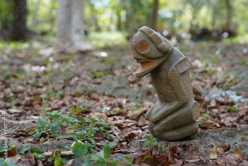 Taino Antique Stone Cemi Idol God Figure standing over rocks on the ground, close up. Taino Mythology. photo