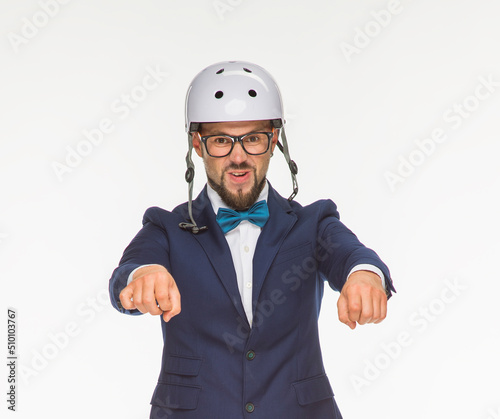 a cheerful guy poses in a white helmet and a blue jacket on a white background isolated in the studio. the guy shows a motorcycle. imitates riding a bike on a motorcycle