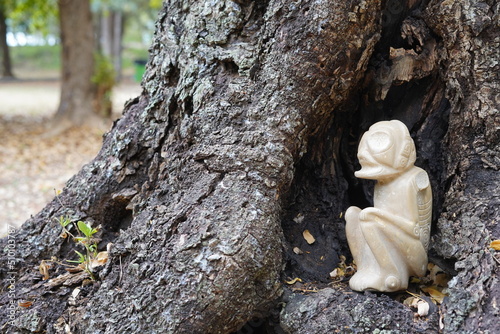 Taino Antique White Stone Cemi Idol God Figure standing on next to a tree, close up. Taino Mythology. photo