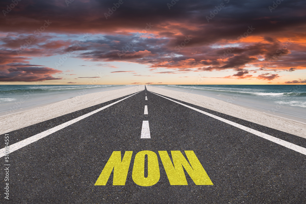 Fototapeta premium Now text on a highway at the beach at sunset. Present moment concept.