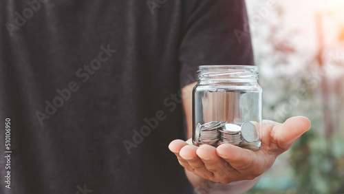 Hand holding a glass jar with money coins inside. The concept of saving money for the future. Financial money concepts and savings. investment  donation  saving  charity  family finance plan concept.