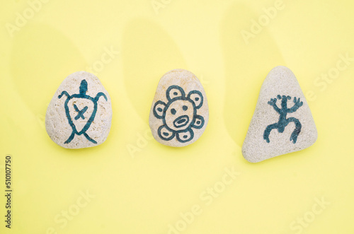 Fototapeta Stones with hand-drawn taino petroglyphs symbols, craft with children for Hispan