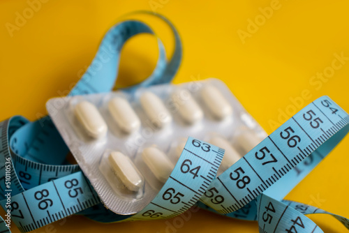 Measuring tape, pills on a light background photo