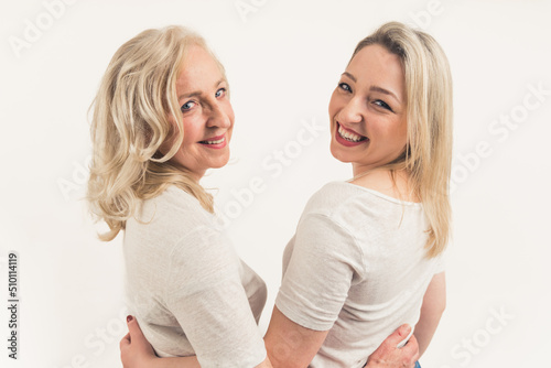 two joyful Caucasian women turning around at the camera and smiling medium closeup isolated on white background studio shot . High quality photo