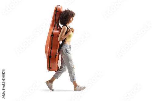 Full length profile shot of a young woman walking and carrying a contrabass in a case on her back