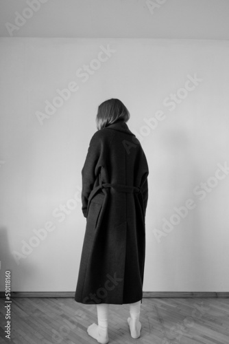 black and white photo of a girl in a black long coat on a light background