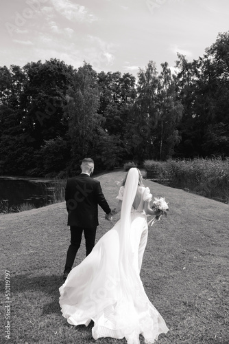 black and white photo of the bride and groom walking on a wedding walk in a beautiful area