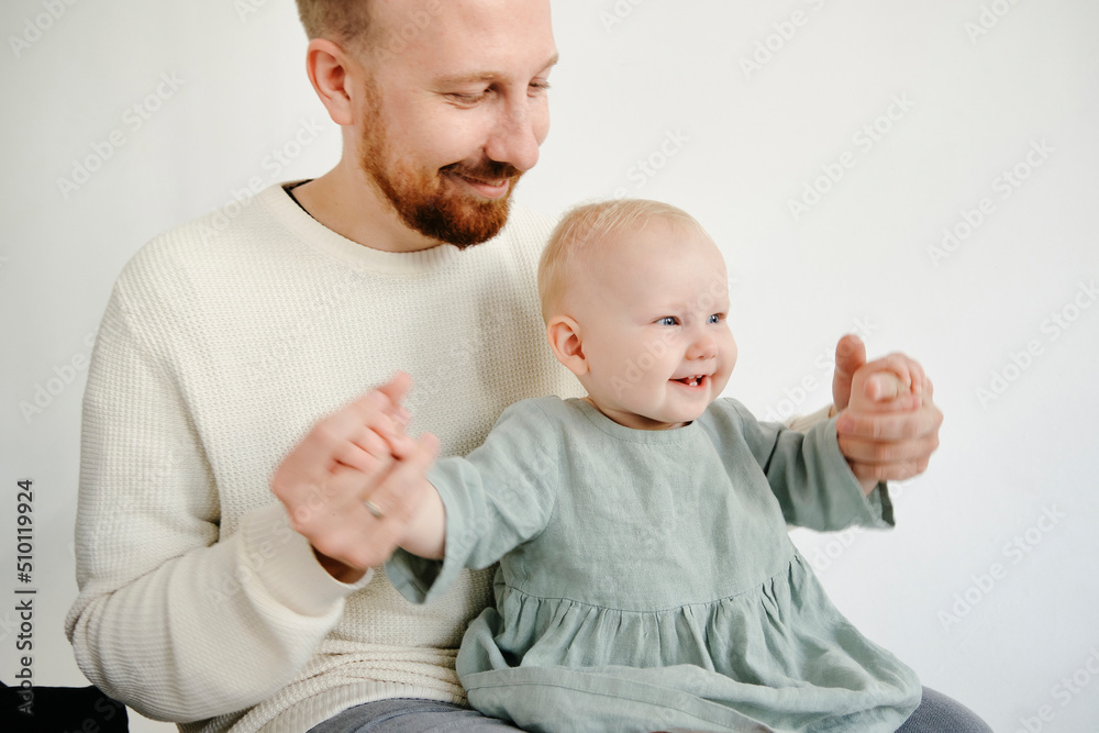 portrait of a happily smiling dad holding the hands of a laughing little daughter portrait of a happily smiling dad holding the hands of a laughing little daughter