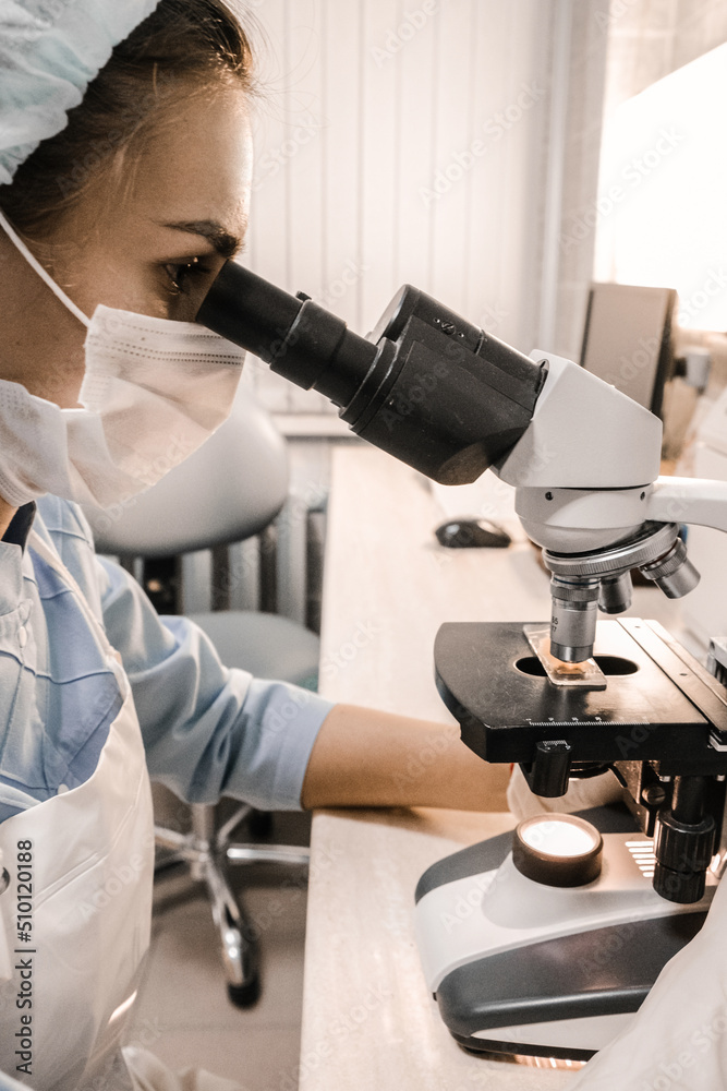 Nurse using a microscope examines blood cells Nurse using a microscope examines blood cells