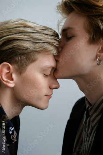 portrait of two guys in love who are opposite each other and one gently kisses the second on the forehead in the studio photo