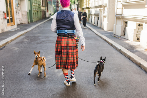 Man with pink hair in a funky kilt walking basenji dogs