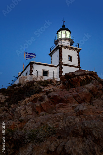 The old lighthouse on the rocky cliff at night.