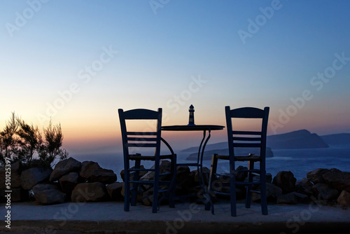 Wooden blue table and chair on the shore of the blue sea. Seaside cafe at evening sunset.