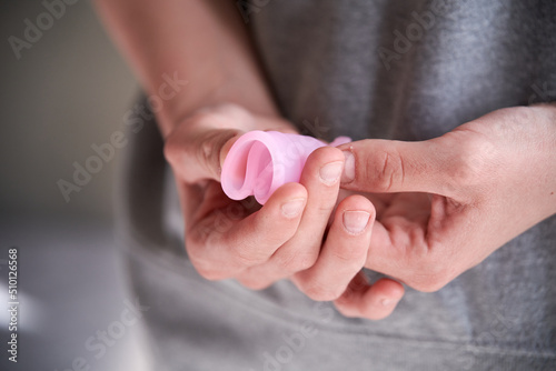 Folded menstrual cup in the hands of a girl photo