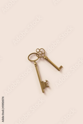 Two antique keys lying connected on beige background photo