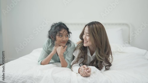 Holiday concept of 4k Resolution. Asian woman lying prone in bedroom. She was looking at the television with interest. photo