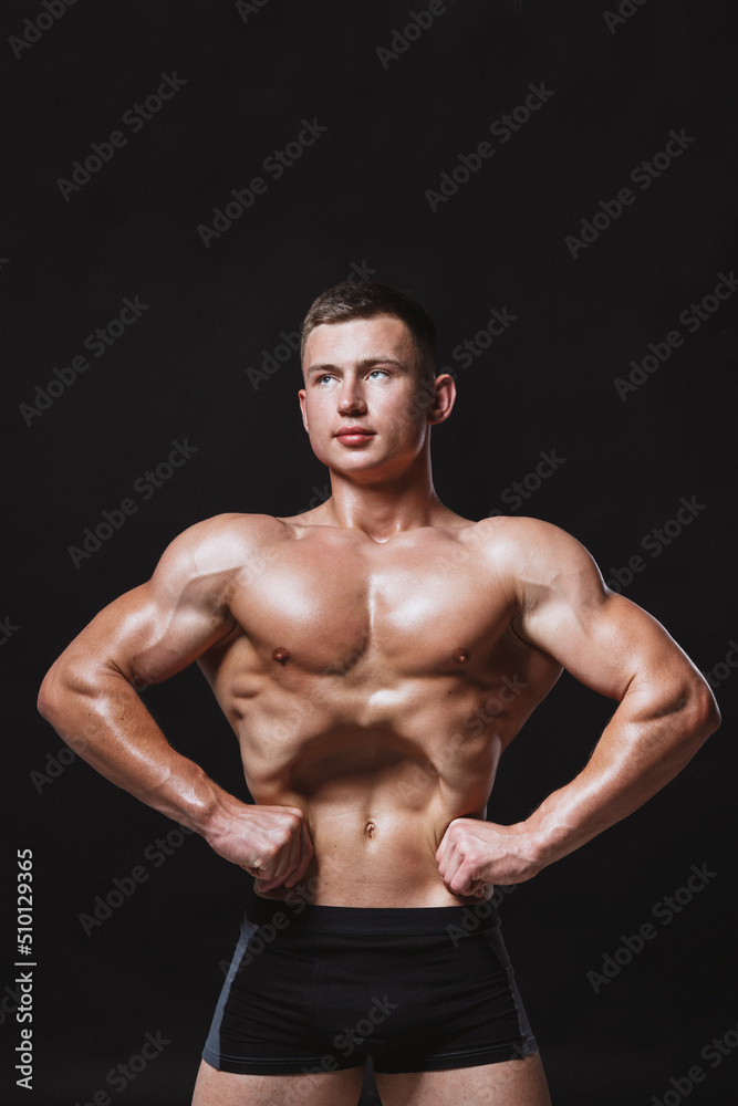 Muscular male model with strong body posing on black background Muscular male model with strong body posing on black background