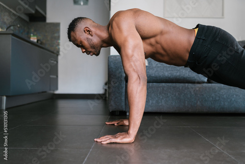 Shirtless muscular black guy doing plank at home photo