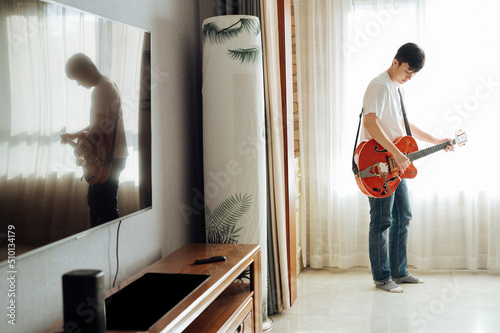 Young man playing guitar at home photo