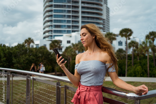 Woman using her mobile phone at the city park in Miami photo