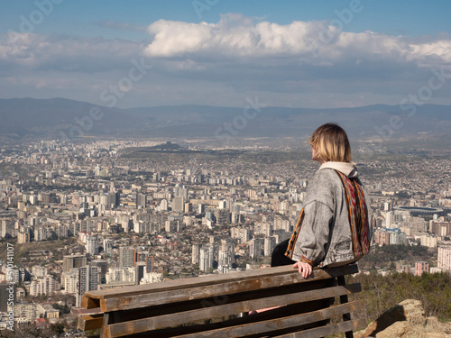 Portrait of a girl on a mountain against the backdrop of a big city