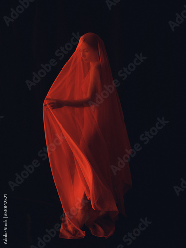 Female figure covered with a red veil photo