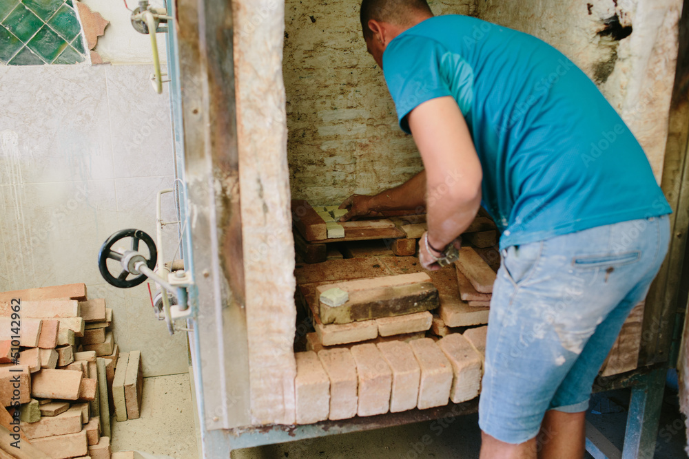 Man putting tiny tiles in an oven Man putting tiny tiles in an oven