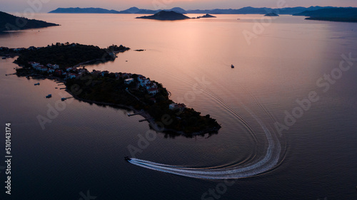 speedboat turning around an island in the sunset