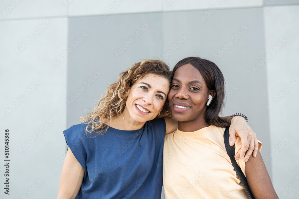 Portrait of two black and white women embracing outdoors in the city Portrait of two black and white women embracing outdoors in the city