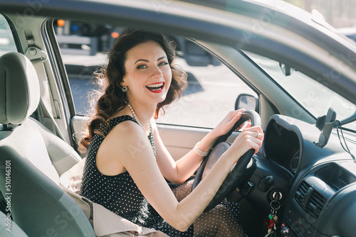 Classically beautiful woman laughing at camera from her car photo