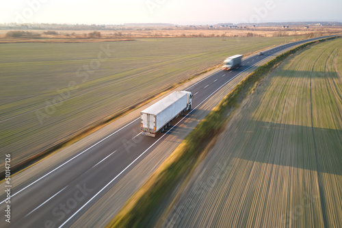 Aerial view of cargo trucks driving on highway hauling goods. Delivery transportation and logistics concept © bilanol