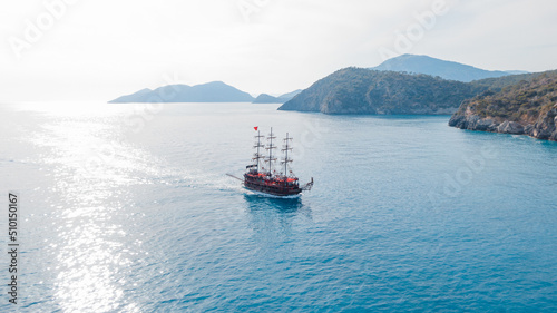 Sailing boat styled as a pirate ship passing by islands
