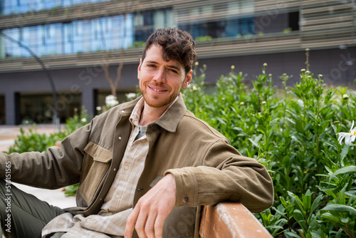 Cheerful man sitting on bench outside building at city  photo