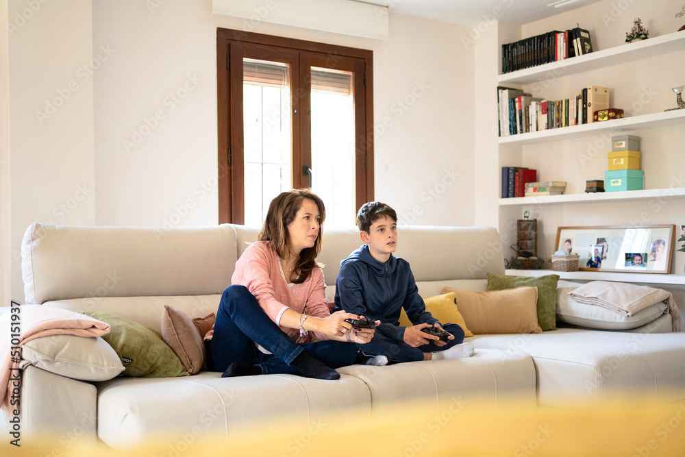 Competing son and mother playing videogame together Competing son and mother playing videogame together