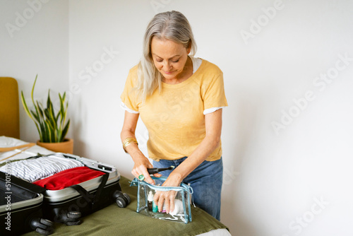Senior woman preparing travel toiletry bag photo