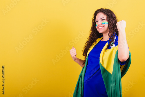 Soccer fan woman, brazil fan, world cup, closed fists, celebrating, cheering for a goal. photo