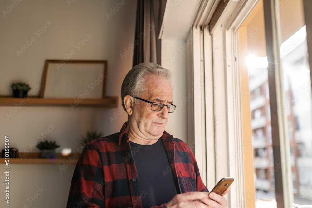 Senior man with vitiligo using mobile phone at home