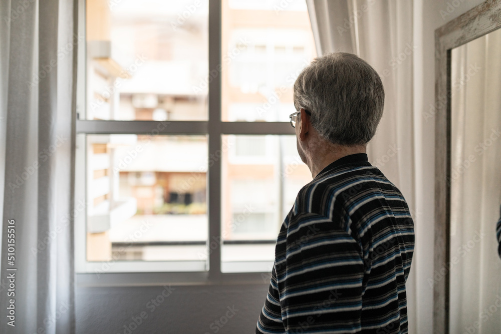 Elderly man looking out the window of his room Elderly man looking out the window of his room