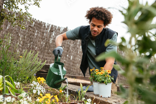 Black male gardener watering plants