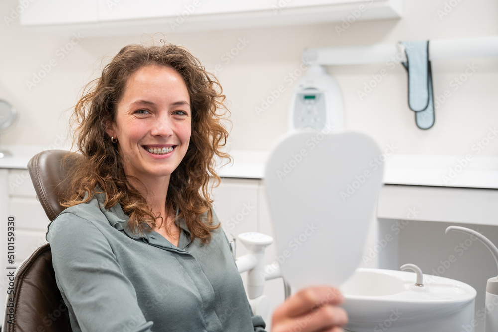 Patient With Clear Braces Holding The Mirror Patient With Clear Braces Holding The Mirror