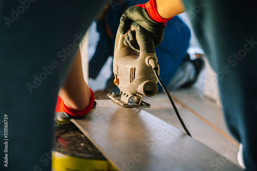 Crop handyman cutting floor plank photo