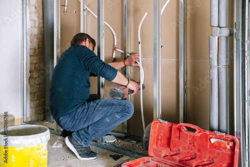 Man installing wall piping in new apartment