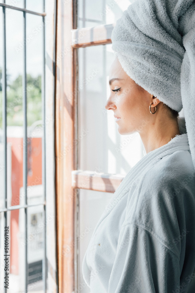 Young woman in white bathrobe take air at the window Young woman in white bathrobe take air at the window