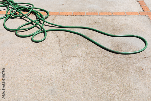 Green garden hose left in the sunshine