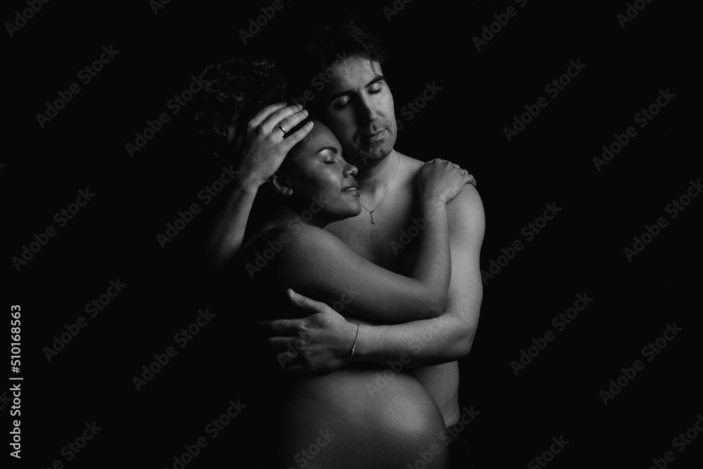Sensual naked pregnant couple hugging in dark room Sensual naked pregnant couple hugging in dark room