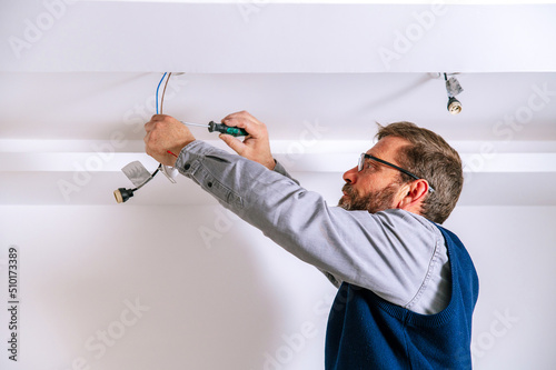 Male electrician installing ceiling illumination photo