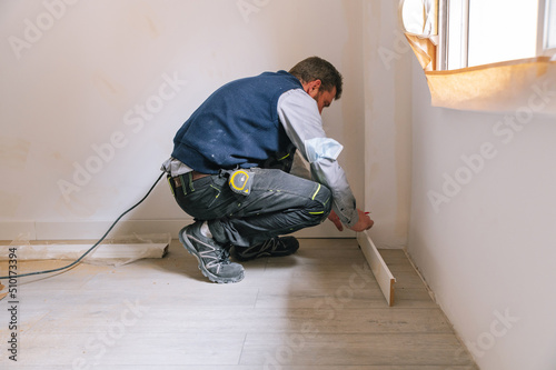 Interior designer installing baseboard planks photo